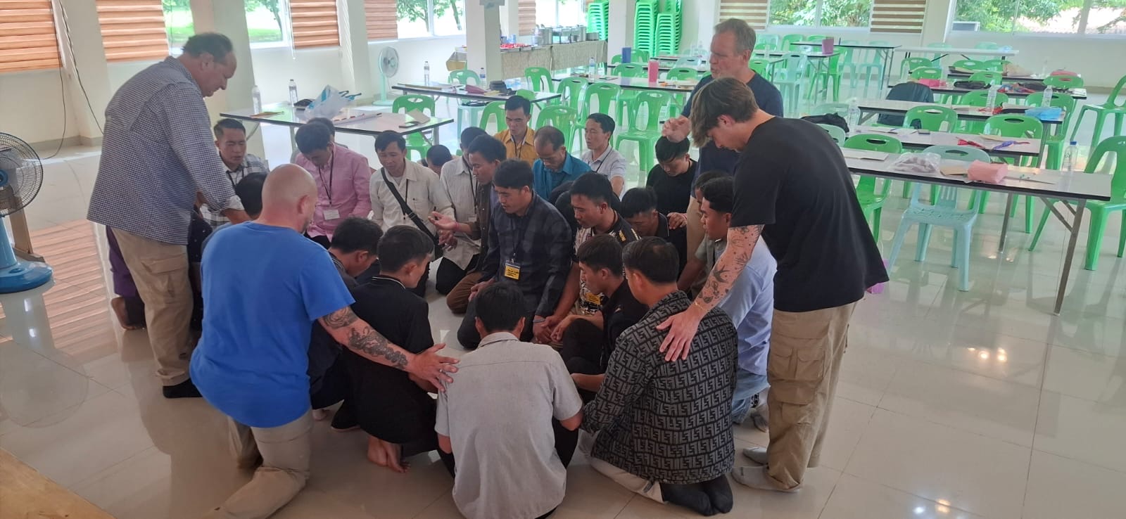 Team and pastors laying hands on a young man in prayer in the dining hall