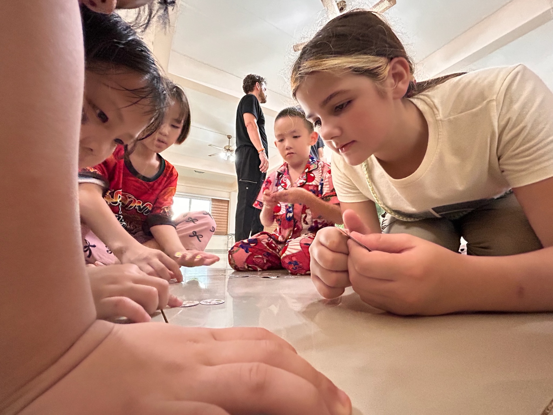 Children huddled over the floor playing the sticker game