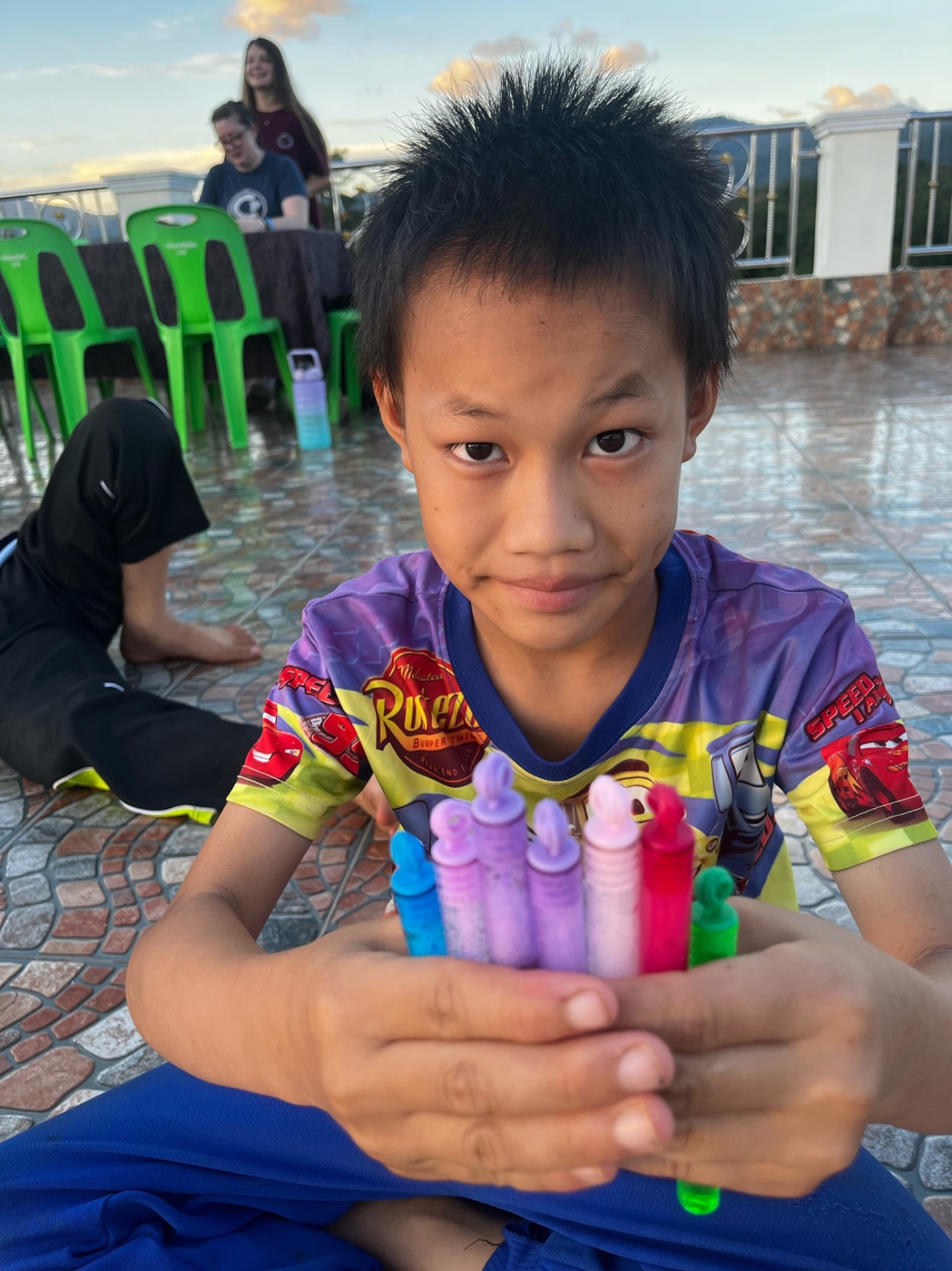 Boy holding a bouquet of bubble bottles up to the camera at sunset