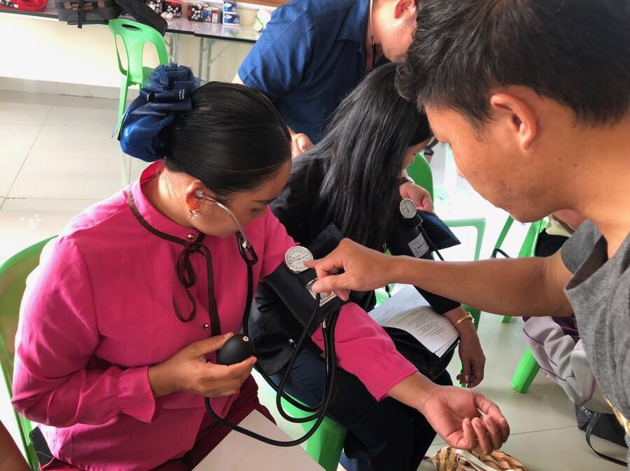 Medical team taking a blood pressure reading on a woman in a pink blouse